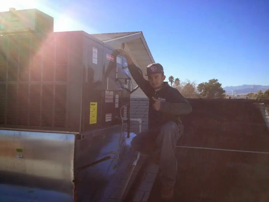 HVAC technician performing Heat Pump Repair on a rooftop unit in Denison