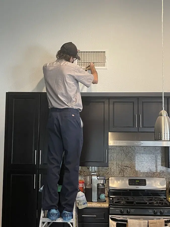 Technician inspecting an air vent during HVAC service in Denison